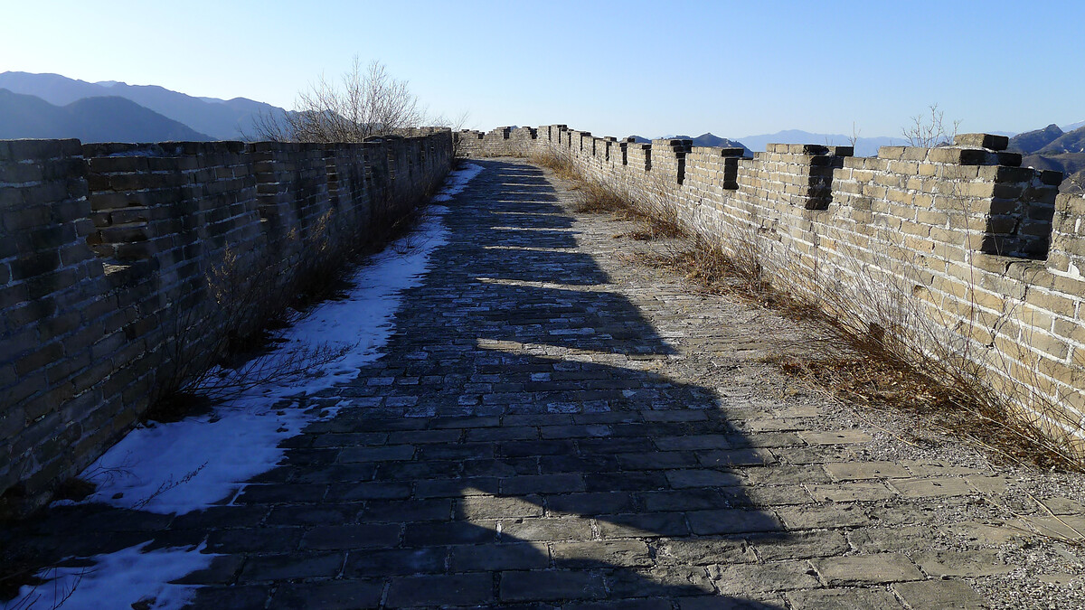 A flat section of Great Wall with long shadows from the battlements.