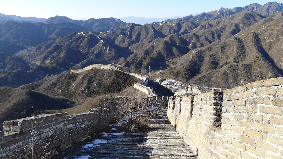 Great Wall leading down to a valley, with more walls in the distant hills.
