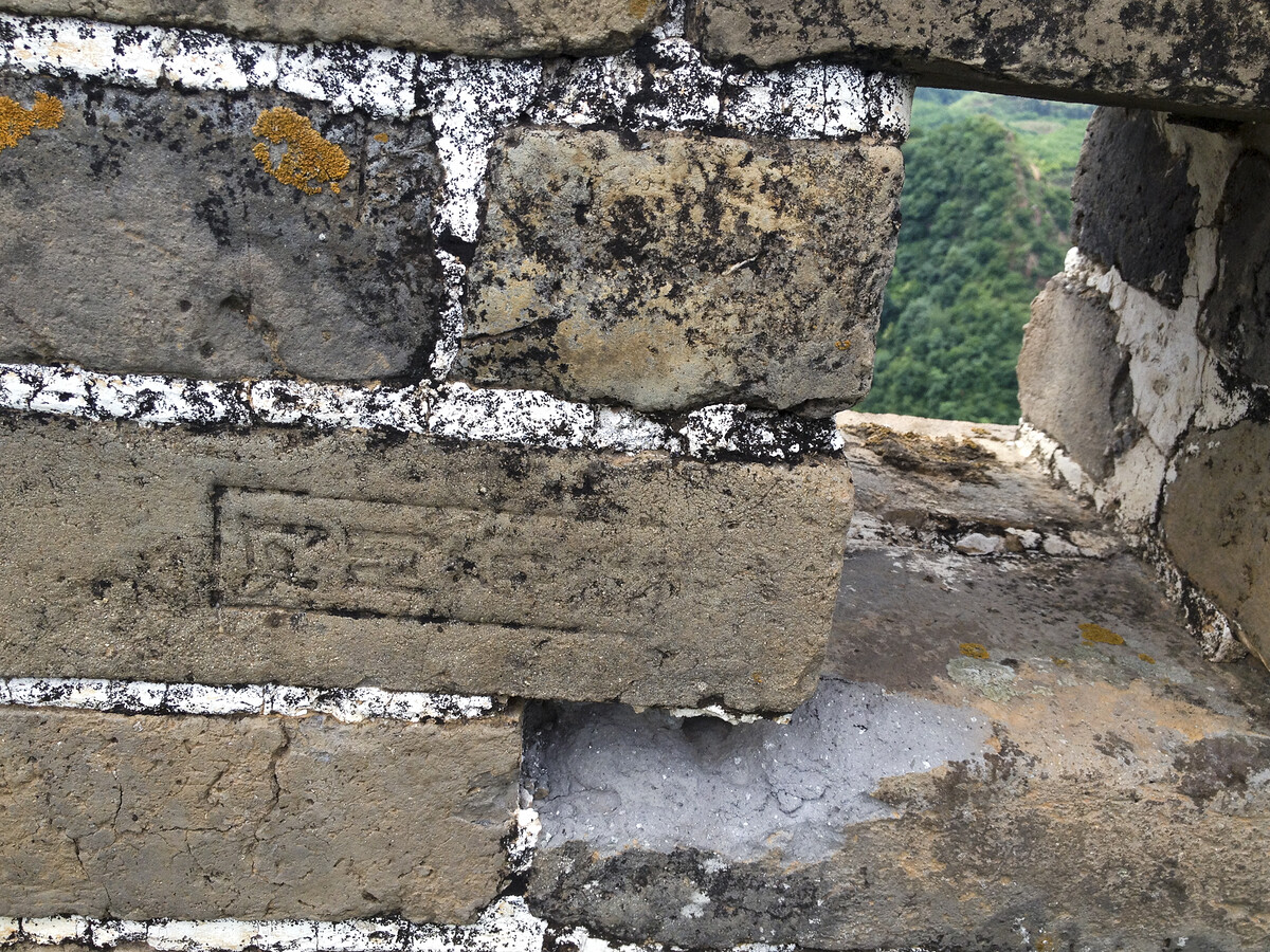 A Great Wall battlement with a stamped brick next to a loophole